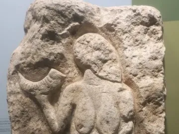 Venus of Laussel limestone relief showing a standing female figure holding a curved horn-like object.