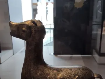 Ciervo de Madinat al Zahra, a dark patterned deer sculpture on a pedestal
