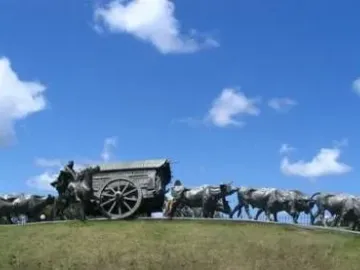 Monument to the Cart sculpture showing a covered cart pulled by oxen with a rider on horseback nearby.