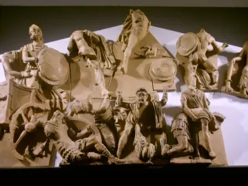 Talamone Pediment terracotta relief with warriors, shields, and a chariot wheel in a dramatic battle scene.