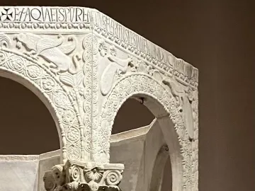 Carved stone arches and ornate columns from the Baptistry of Callistus, with reliefs of birds, foliage, a cross, and an inscription.