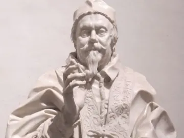 Marble bust of Clemente X wearing an ornate ecclesiastical garment, with a cap, rosary, and book.