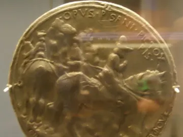 Medal of John VIII Palaiologos showing a round gold-colored relief with figures on horseback and inscriptions around the edge.