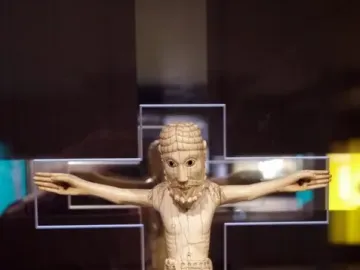 Carrizo Christ crucifix with outstretched arms, carved details, and a decorated loincloth displayed in a case.