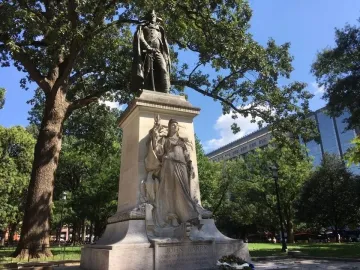 Commodore John Barry statue atop a tall stone pedestal with a Victory relief in a park
