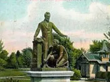 The Emancipation Memorial shows Abraham Lincoln standing over a kneeling man with a broken chain on a tall pedestal in a park.