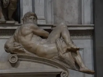 Michelangelo’s Day, a reclining marble male figure with drapery over the lower body.
