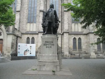 New Bach Monument statue of Johann Sebastian Bach on a stone pedestal in front of a historic church building