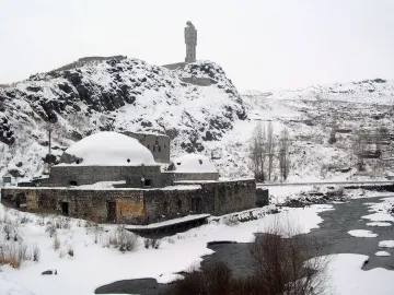 Statue of Humanity on a snowy rocky hill, showing two slender figures facing each other with their arms reaching toward the center.