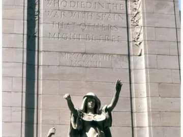 USS Maine National Monument with three allegorical figures below an inscribed stone wall.