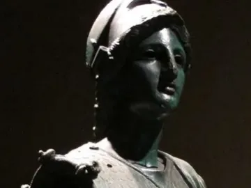 Upper portion of Minerva d\'Arezzo showing a helmeted female figure with a scaly chestplate and a small head relief on the aegis.