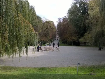 Table of Silence stone sculpture with round table and hourglass-shaped stools in a park lined with trees