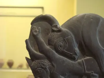 Bull Palette carved stone fragment showing a bull\'s head and forebody with a human figure reaching toward it.