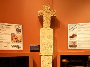Padrão stone pillar with a cross top displayed in a museum exhibit.