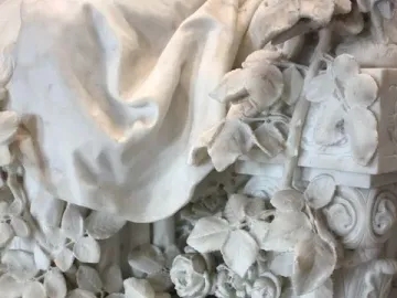 Sleeping Beauty marble sculpture detail with roses, drapery, and a spindle beside an ornate pillar.