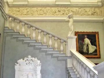 Sleeping Beauty marble sculpture seated in an ornate armchair beside a grand staircase