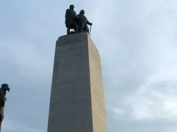 This Is the Place Monument with bronze pioneer statues on top and covered wagon sculptures around the base.