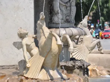 Lower section of the Genio Catalán Fountain with a winged figure and hippocampus sculptures flowing with water.