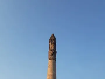 The Roundabout of the Disappeared monument with a tall stone column, statues at the top and base, and a banner reading \