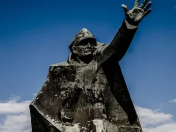 Kościuszkowców Memorial with a skateboarder performing a trick beside the bronze monument