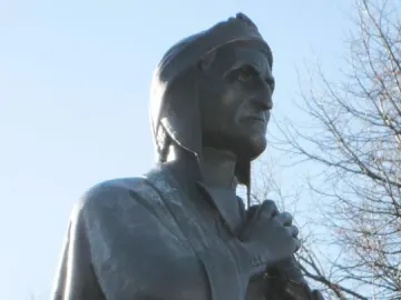 La mort de Dante sculpture shown in close-up, with a dark bronze figure in a cap and draped clothing against the sky.