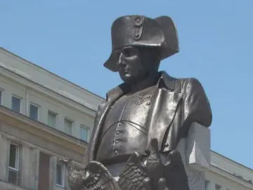 Bronze bust of Napoleon I on a tall stone plinth decorated with eagles, a crown, and the letter N.