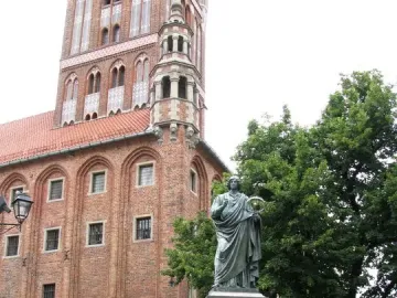 Nicolaus Copernicus Monument showing a bronze robed figure holding an astrolabe and pointing upward in a city square.