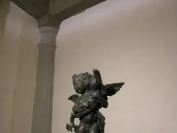 Bronze putto with a dolphin, the winged child poised on one foot atop a small base.