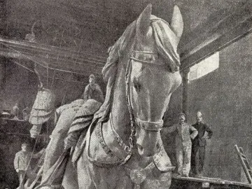 A giant equestrian statue of Victor Emmanuel II under construction in a workshop, with several men standing nearby.