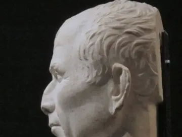 Arles Bust in white marble, shown in left profile against a dark background.