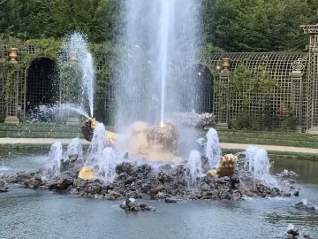 Enceladus Fountain with a golden statue rising from dark rocks as water jets spray around it.