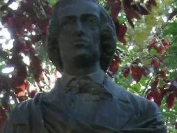 Frédéric Chopin bust with wavy hair above a mossy stone marker.
