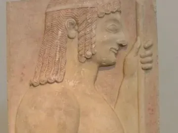 Grave stele relief of a young doryphoros in profile, holding a vertical staff against a red background.