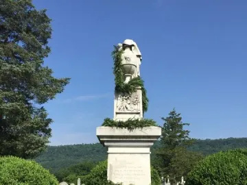 Confederate Memorial stone monument topped by an urn, with green garland and small Confederate flags around the base.