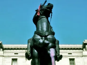 Equestrian statue of Francisco Franco on a stone pedestal with a flower wreath at the base.