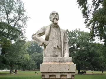 Busto of Ernesto Teodoro Moneta on a tall inscribed pedestal in a grassy park.