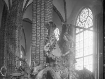 Saint George and the Dragon sculpture showing a knight on a rearing horse above a dragon inside a church interior.