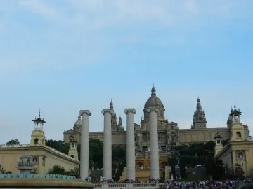 The Four Columns in front of a large hilltop museum building, with a crowd gathered below.
