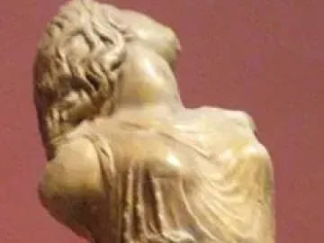 Dancing Maenad sculpture with the figure’s head tilted back and flowing drapery against a red-brown background.