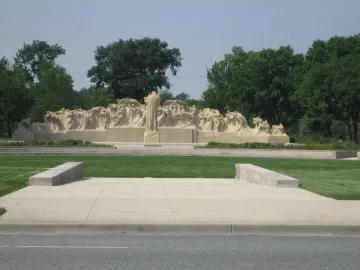 Fountain of Time stone monument with a central robed figure and smaller sculpted figures arranged in a wave-like form.