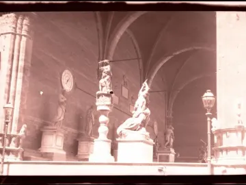 Judith and Holofernes sculpture on a tall pedestal in a grand arched hall with surrounding statuary.