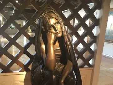 La Douleur, a dark metal sculpture of a seated woman resting her head on her hand.