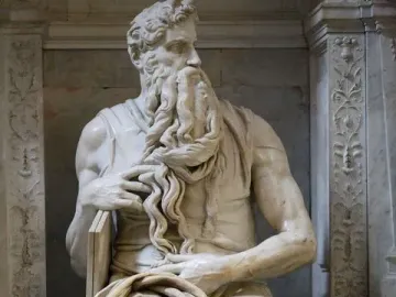Michelangelo\'s Moses, a seated marble statue of a bearded man with horns holding tablets under his arm.