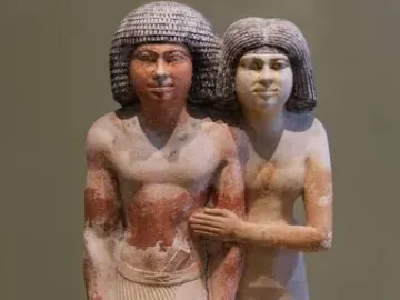 Painted ancient Egyptian statue of Raherka and Meresankh standing together on a rectangular base.