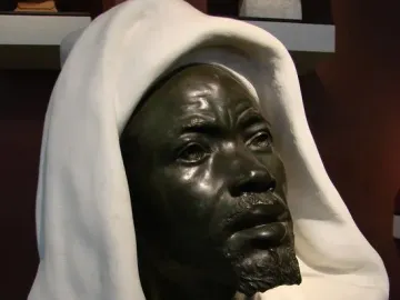 Salem, Negro of Sudan, a dark metal bust of a bearded man in a white hooded garment.