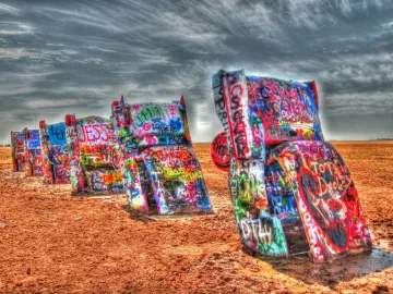 Cadillac Ranch with several vintage car bodies buried nose-down and covered in colorful graffiti.