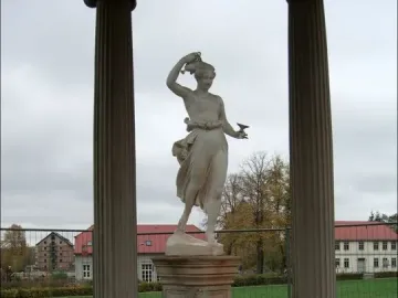 Classical statue of Hebe holding a jug and cup between two fluted columns.