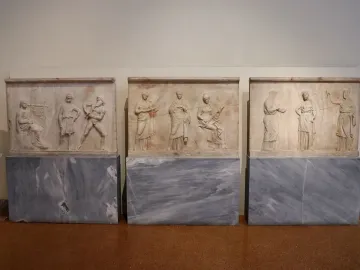 Mantineia Base relief slabs showing classical figures, including musicians and seated or standing characters, displayed side by side.