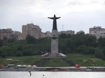 Mother Patroness statue on a tall pedestal, overlooking a landscaped hill and staircase.