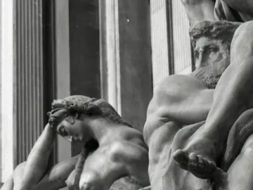 Detail of Michelangelo’s Night sculpture, showing a reclining female figure with her head resting on her hand beside a partial male figure and mask.